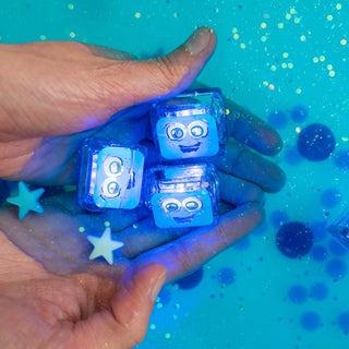 Hand holding glowing blue cubes with  faces against a blue water background