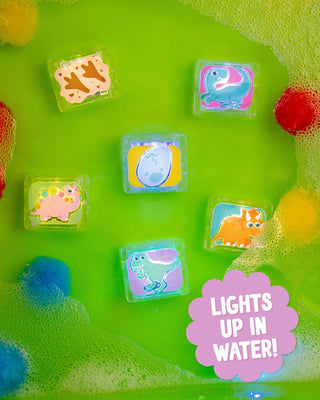Colorful dinosaur-themed bath toys on a green surface with water and bubbles.