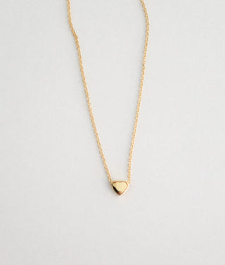 Gold necklace with a heart pendant on a light gray background
