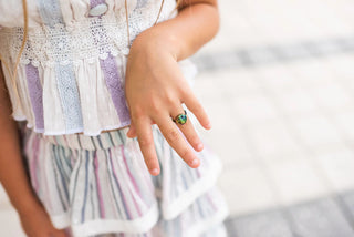 Child's hand wearing a rainbow smiley face ring with a blurred background