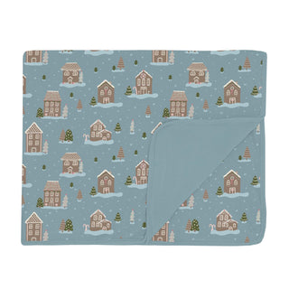 Folded blanket with a winter gingerbread village pattern on a blue background