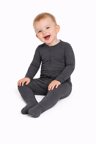 Child wearing a dark gray onesie on a white background