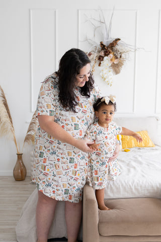 Woman and child in matching pajamas standing in a bedroom.