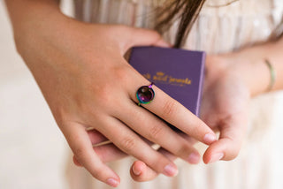 Person wearing a colorful ring with a purple box labeled 'Jack and Jewelz' on a light background