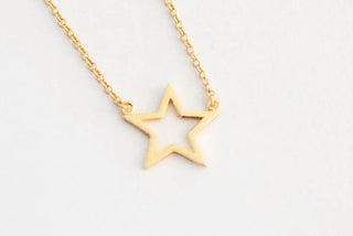 Gold star-shaped pendant necklace on a light gray background