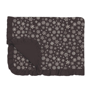 Black folded blanket with a black ruffle edge with white snowflake pattern on a white background
