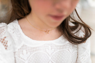 Person wearing a gold star-shaped necklace on a blurred background