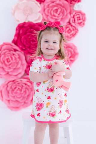 Child in a floral dress standing in front of pink flower decorations