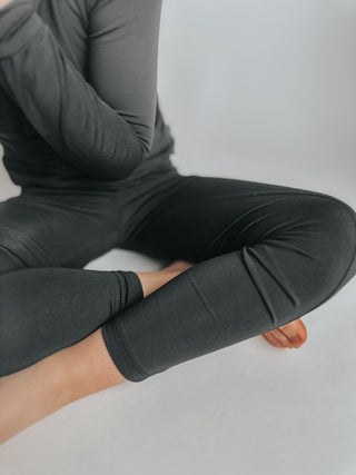 Person wearing black leggings sitting on a white surface