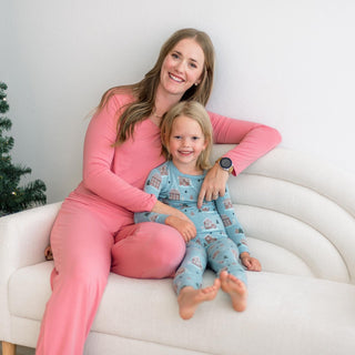 Woman and child in matching pajamas sitting on a white couch.