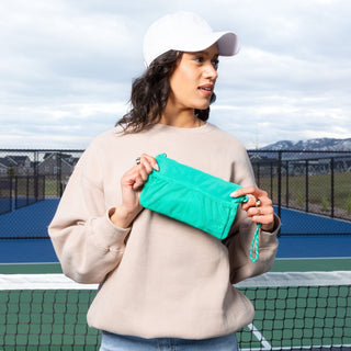 Woman holding a green towel on a tennis court