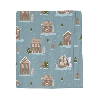 Blanket with gingerbread house pattern featuring houses and trees on a blue background