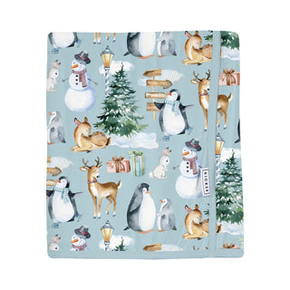 Blanket with winter-themed design featuring penguins, deer, and snowmen on a blue background.