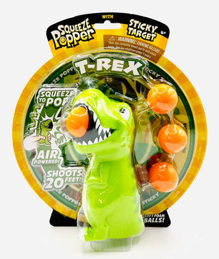 Green dinosaur toy with orange balls in packaging labeled 'Squeeze Popper T-Rex'.