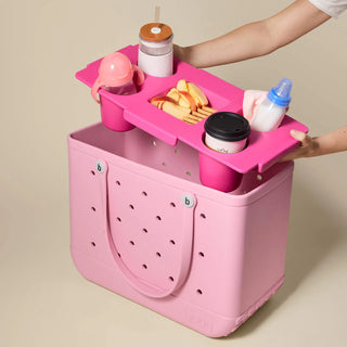 Pink portable snack tray with food items on a beige background
