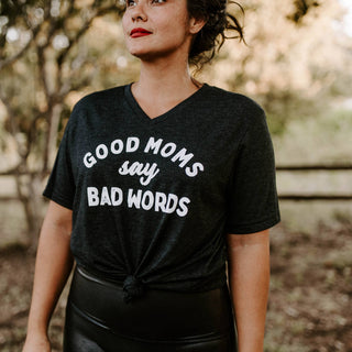Woman wearing a black t-shirt with 'Good moms say bad words' text outdoors.