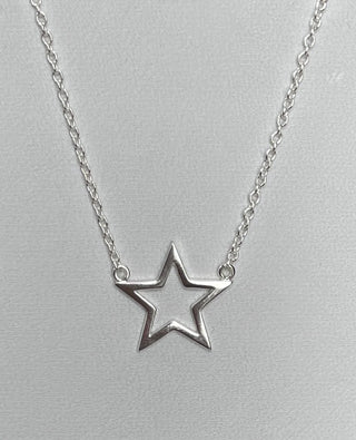 Silver star-shaped pendant on a chain against a light gray background