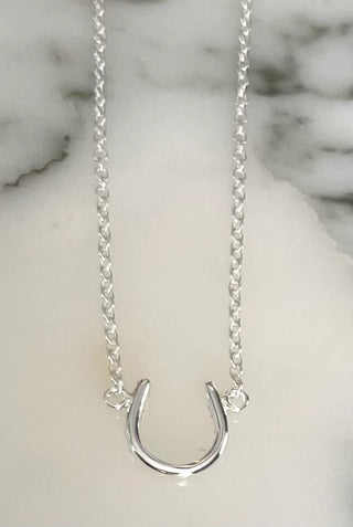 Silver horseshoe necklace on a marble surface