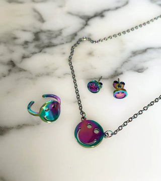Jewelry set with rainbow-colored earrings, ring and necklace on a marble surface